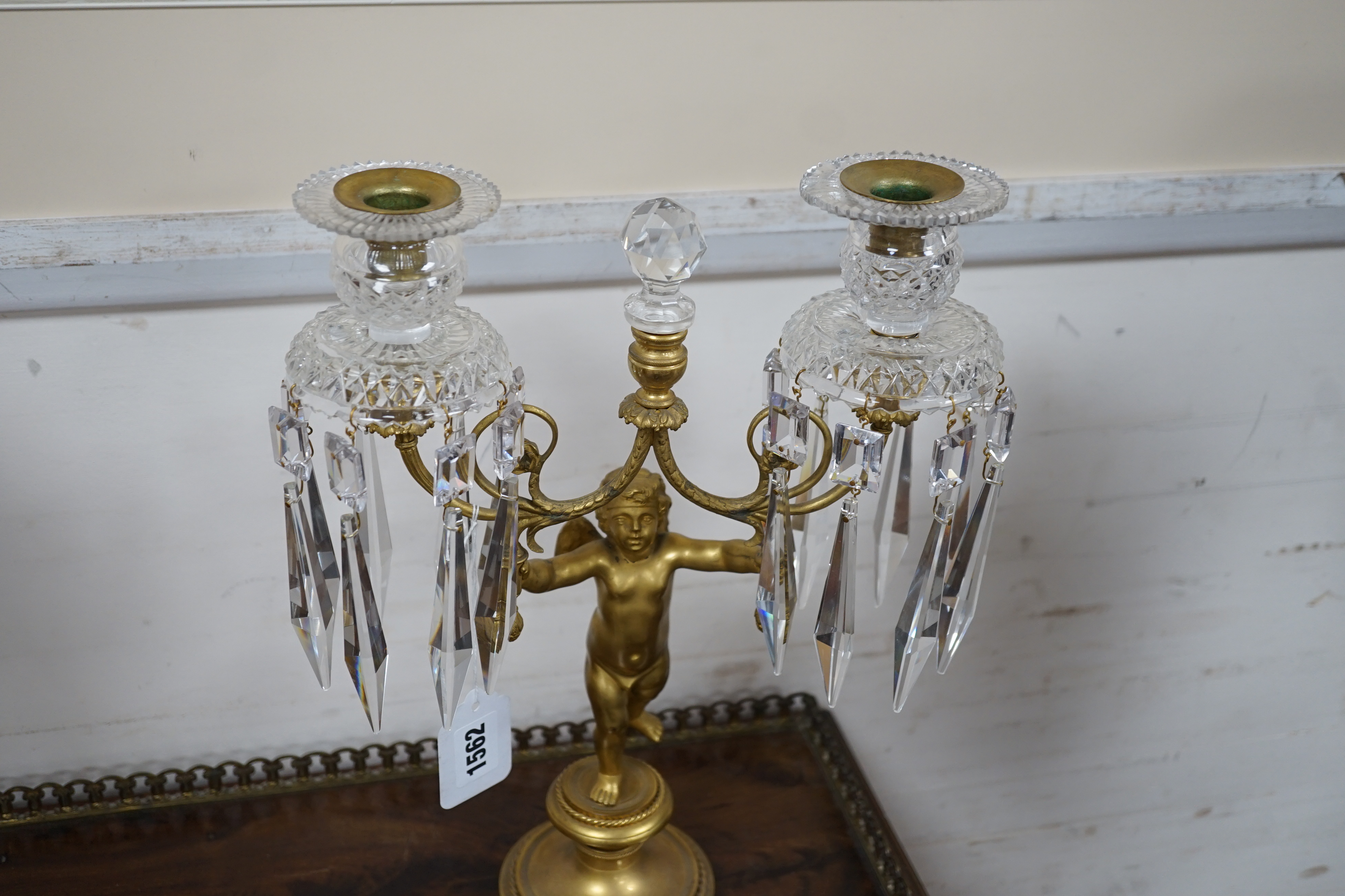 A pair of Regency ormolu ‘Cupid’ two branch glass lustre candelabra, 37cm high